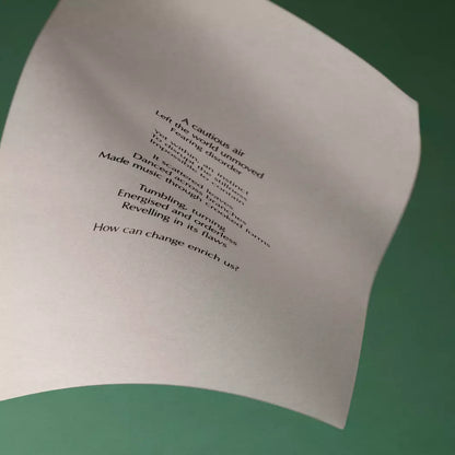 Curved cream page with printed verse against a dark brown background.