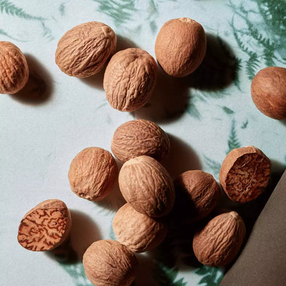 Scattered whole nutmegs on a dark surface.
